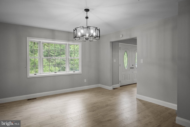 unfurnished room with a chandelier and light hardwood / wood-style floors