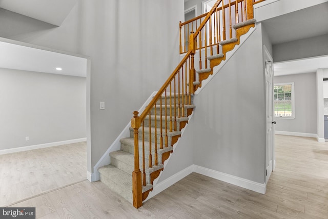 staircase featuring hardwood / wood-style floors and a towering ceiling