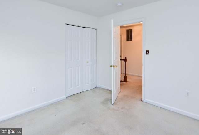 unfurnished bedroom with light colored carpet and a closet