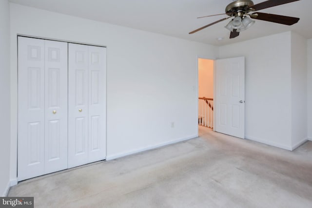 unfurnished bedroom featuring ceiling fan, light carpet, and a closet