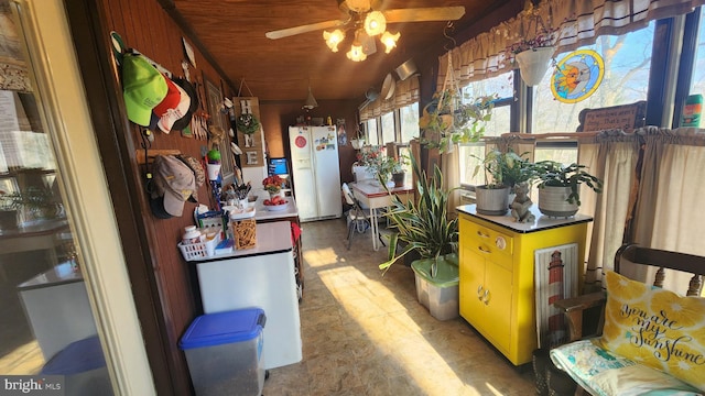 misc room with ceiling fan, wooden walls, and vaulted ceiling