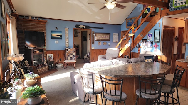 interior space featuring wood walls, lofted ceiling, crown molding, a brick fireplace, and ceiling fan