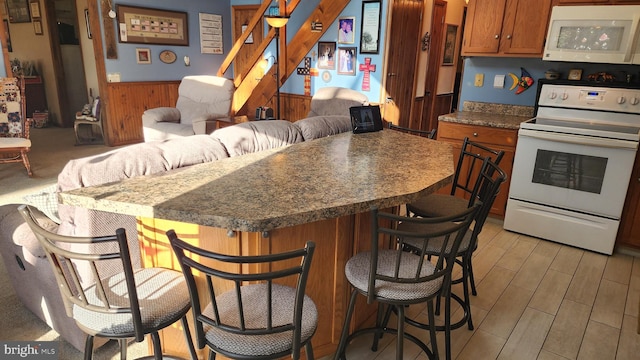 kitchen with white appliances, a breakfast bar area, and wood walls