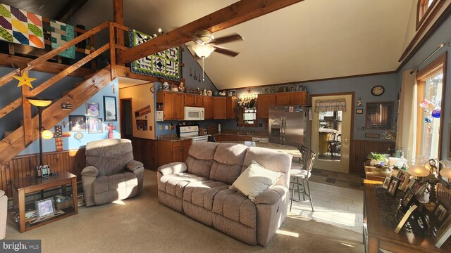 carpeted living room with ceiling fan, sink, beamed ceiling, high vaulted ceiling, and wood walls