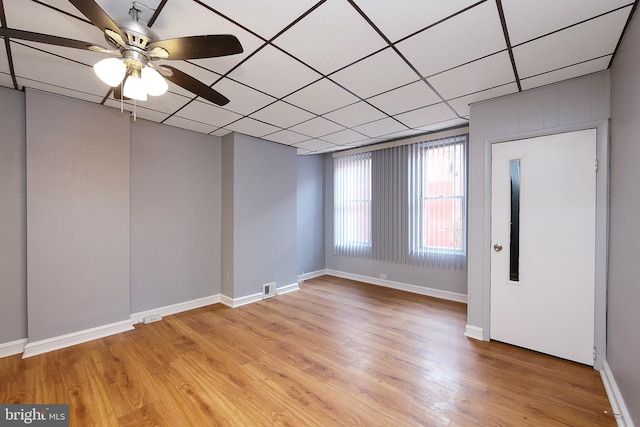 empty room featuring light wood-type flooring, ceiling fan, and a paneled ceiling