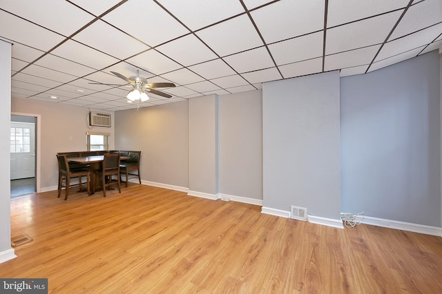 dining room with a wall mounted air conditioner, ceiling fan, a drop ceiling, and light hardwood / wood-style flooring