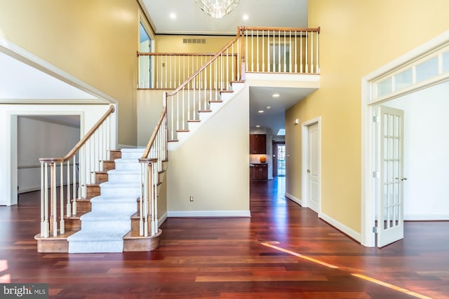 staircase with wood-type flooring, a towering ceiling, and french doors