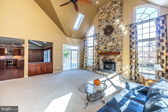 living room with ceiling fan, carpet floors, high vaulted ceiling, and a skylight