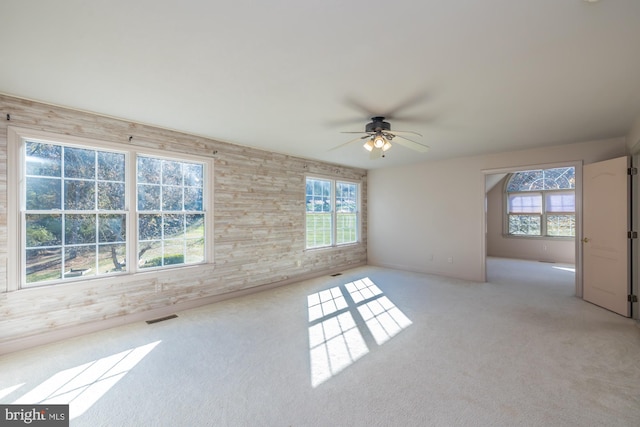 carpeted empty room with ceiling fan and plenty of natural light