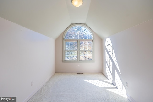 empty room with light colored carpet and vaulted ceiling