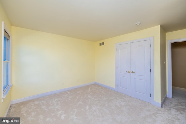 unfurnished bedroom featuring light colored carpet and a closet