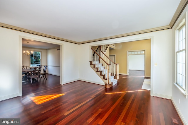 spare room featuring crown molding, plenty of natural light, dark hardwood / wood-style floors, and a notable chandelier