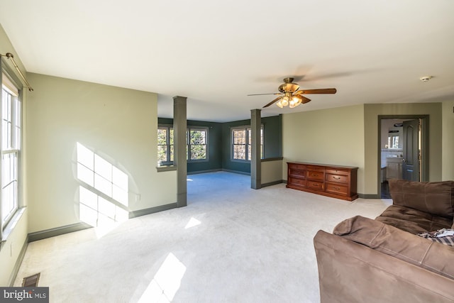 living room with ornate columns, ceiling fan, plenty of natural light, and light colored carpet