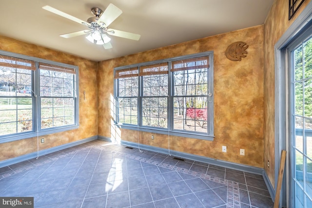 spare room featuring ceiling fan and dark tile patterned flooring