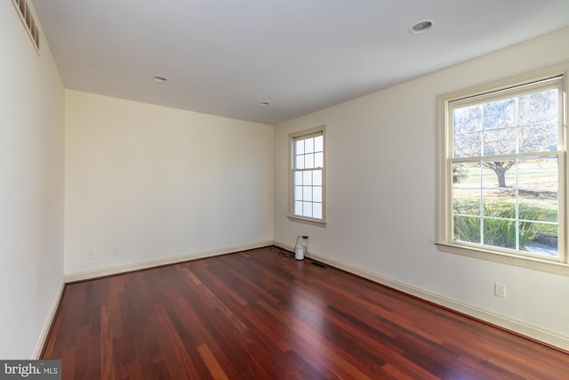 spare room featuring dark hardwood / wood-style flooring and a healthy amount of sunlight