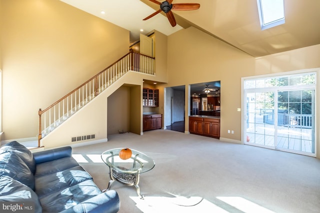 living room featuring ceiling fan, light colored carpet, and a high ceiling