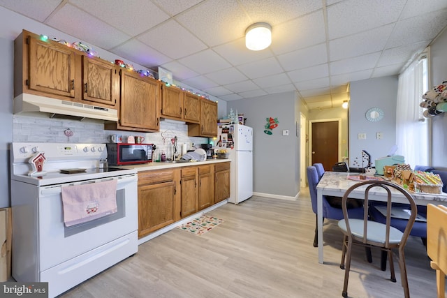 kitchen with decorative backsplash, white appliances, light hardwood / wood-style flooring, and a drop ceiling