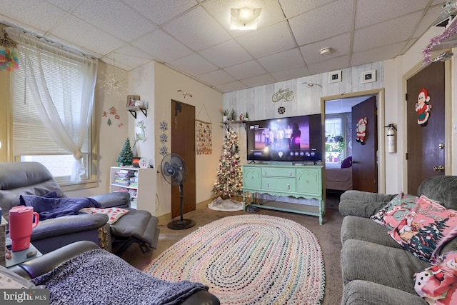 living room featuring a drop ceiling and carpet floors