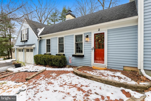 snow covered property entrance with a garage