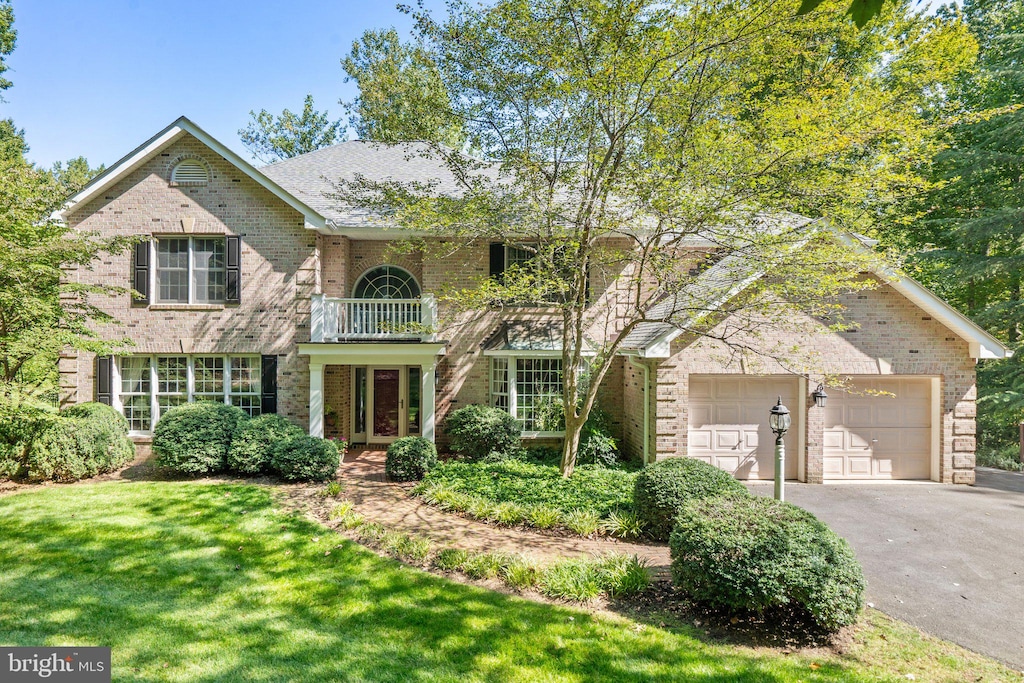 view of property featuring a garage, a balcony, and a front yard