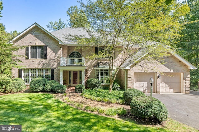 view of property featuring a garage, a balcony, and a front yard