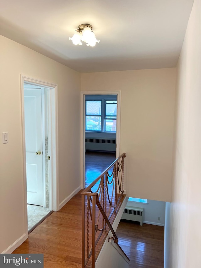 corridor with radiator heating unit and hardwood / wood-style flooring