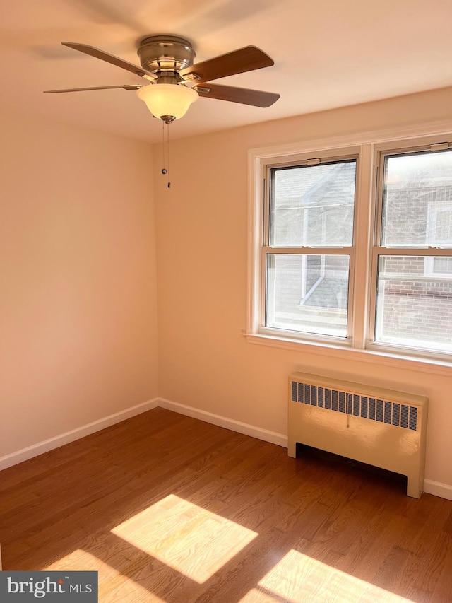 unfurnished room featuring radiator heating unit, light hardwood / wood-style flooring, a wealth of natural light, and ceiling fan