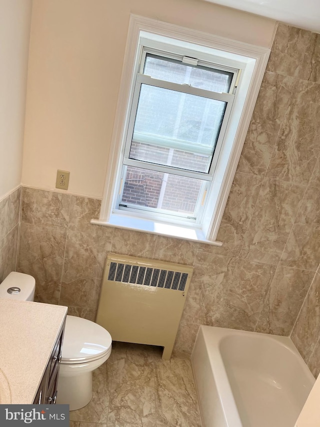 bathroom featuring radiator heating unit, a bathtub, a healthy amount of sunlight, and toilet