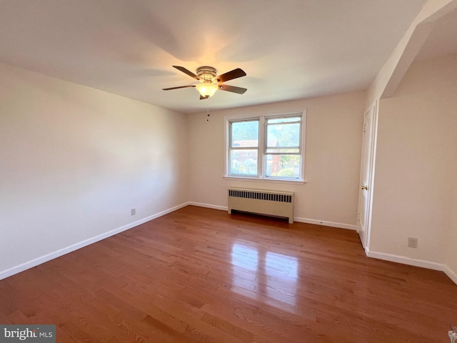 unfurnished room featuring radiator heating unit, hardwood / wood-style flooring, and ceiling fan