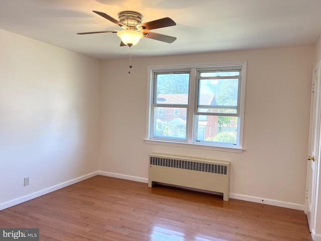 unfurnished room with ceiling fan, radiator heating unit, and light wood-type flooring