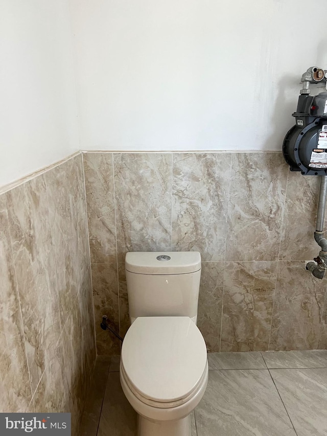 bathroom featuring tile patterned floors, tile walls, and toilet