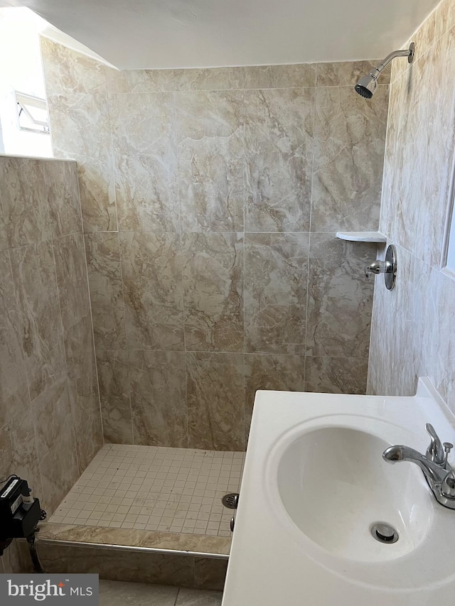 bathroom with tiled shower and sink