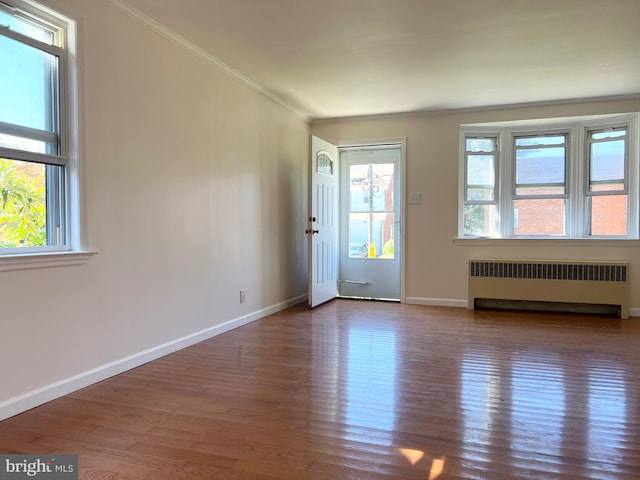 entrance foyer featuring radiator, crown molding, and hardwood / wood-style flooring