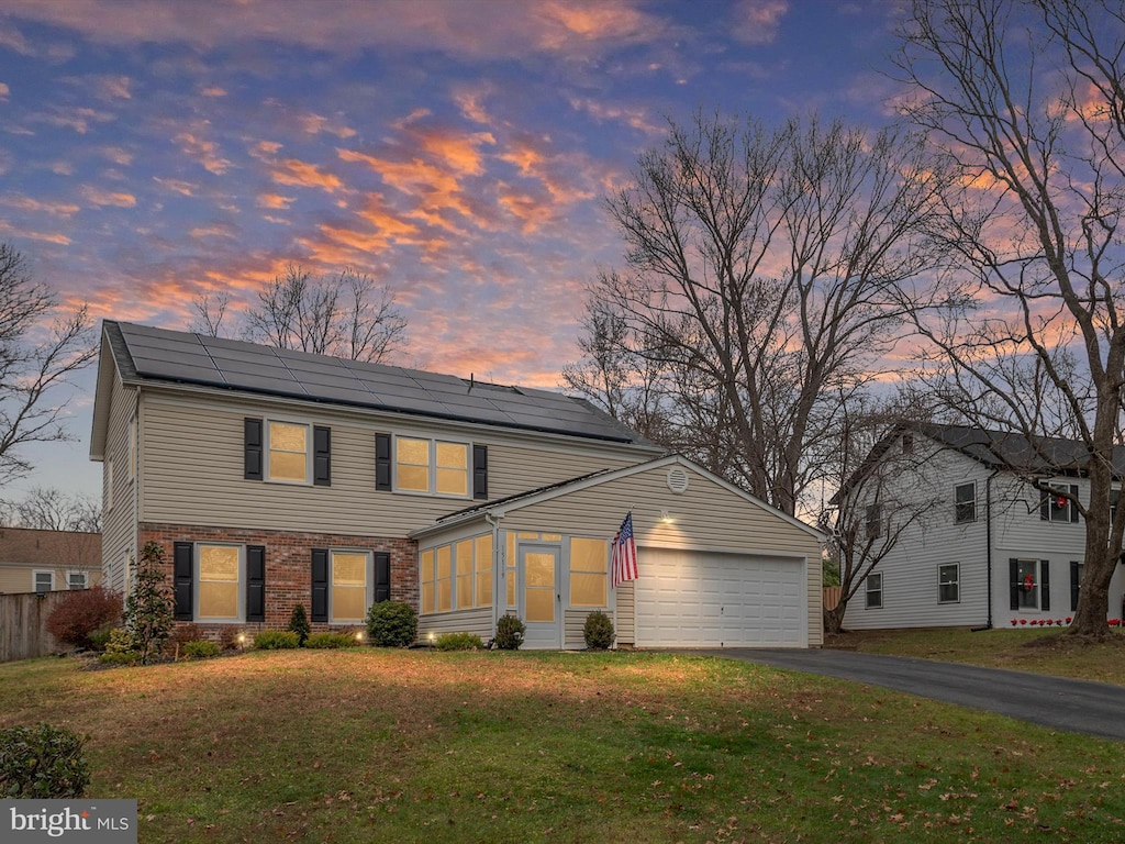 view of front of house featuring solar panels, a yard, and a garage