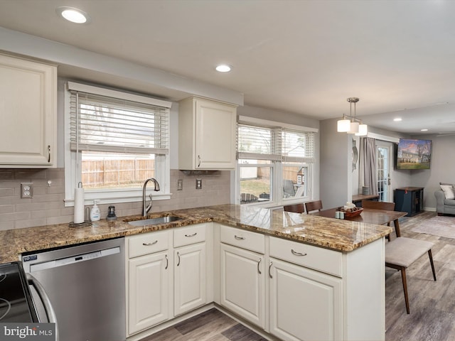 kitchen featuring light hardwood / wood-style floors, dishwasher, hanging light fixtures, and sink