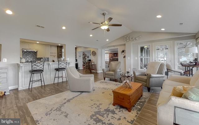 living room with ceiling fan, light hardwood / wood-style floors, and lofted ceiling