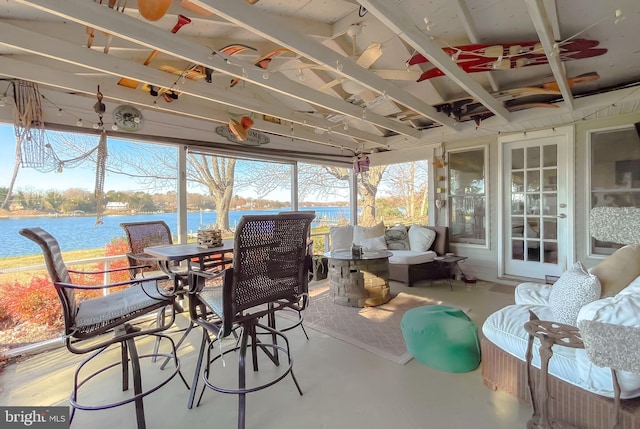 sunroom / solarium featuring ceiling fan and a water view