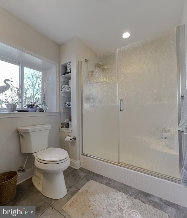 bathroom with a shower with shower door and toilet