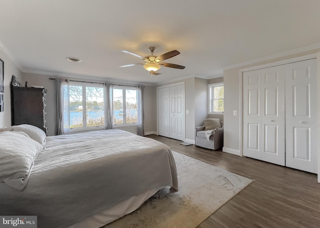 bedroom featuring multiple windows, dark hardwood / wood-style floors, ceiling fan, and ornamental molding