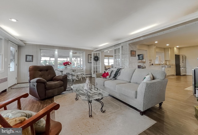 living room featuring a wealth of natural light, crown molding, and wood-type flooring