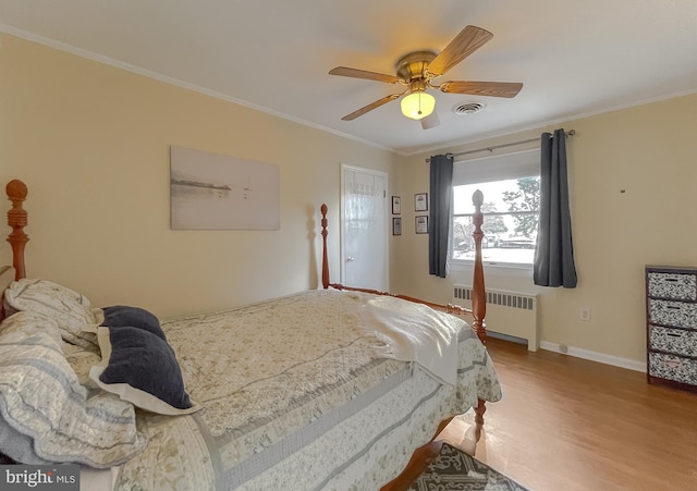 bedroom with radiator, ceiling fan, crown molding, and wood-type flooring