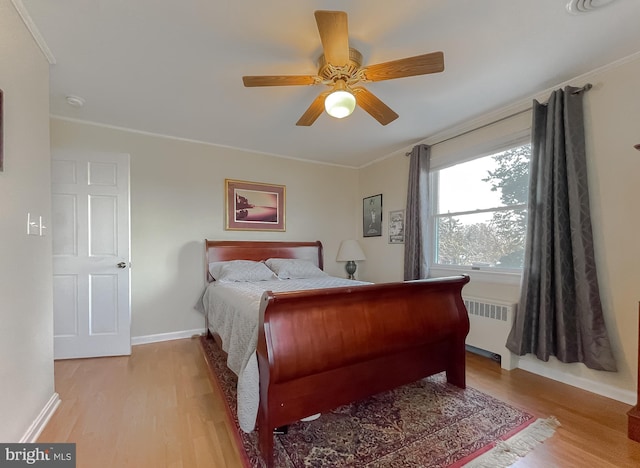 bedroom with ceiling fan, crown molding, radiator, and light hardwood / wood-style flooring