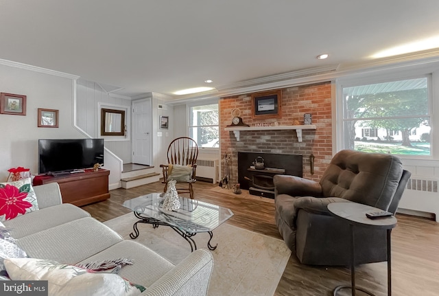 living room with wood-type flooring, a wood stove, radiator, and crown molding