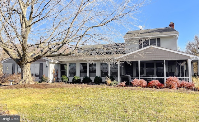 rear view of property featuring a yard and a sunroom