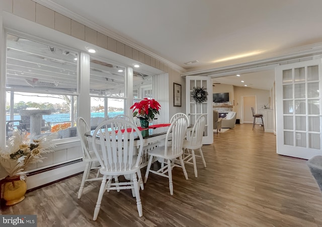 dining space featuring hardwood / wood-style flooring, baseboard heating, and ornamental molding