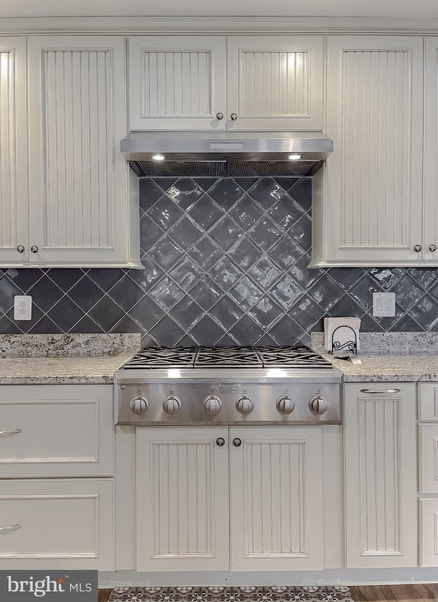 kitchen with backsplash, light stone counters, white cabinetry, and stainless steel gas cooktop