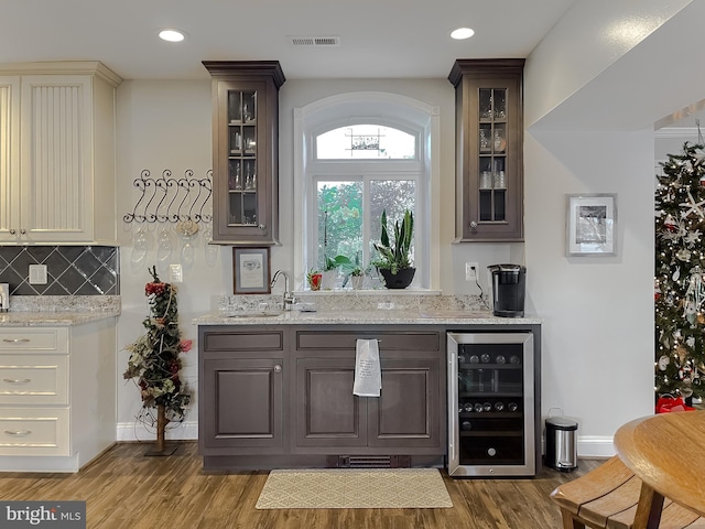 bar with dark hardwood / wood-style flooring, sink, beverage cooler, and cream cabinets