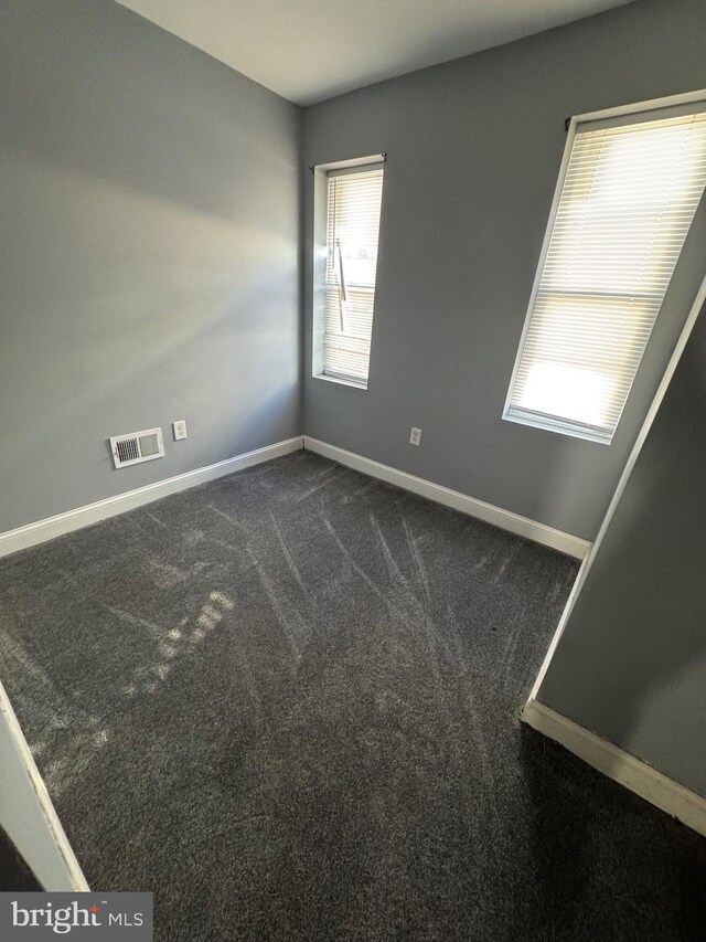 unfurnished room with dark colored carpet