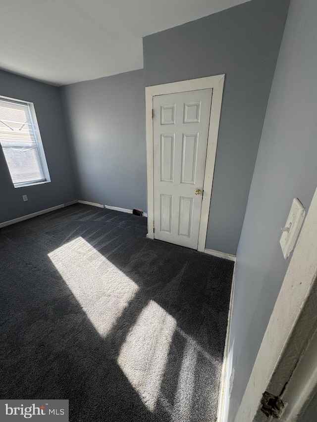 unfurnished room with dark colored carpet