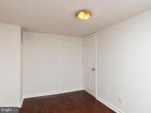 unfurnished room with dark wood-type flooring